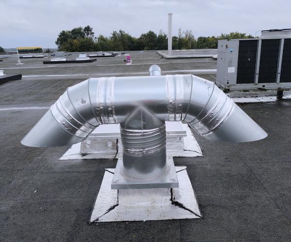 Système de gaines et tuyauteries pour ventilation industrielle dans un bâtiment, mis en place par une entreprise de ventilation.
